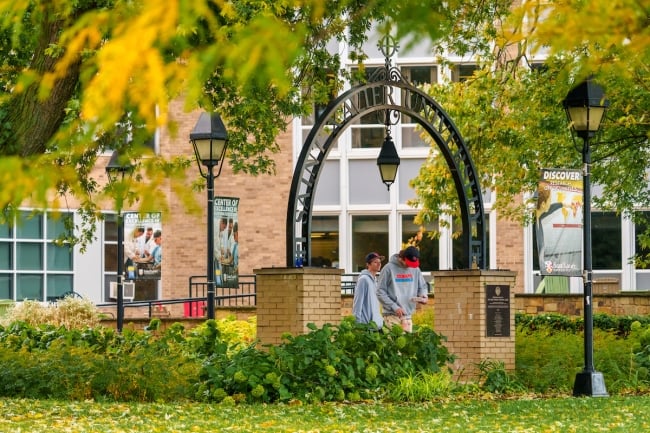 Two students walk on Saint Xavier's campus during the fall. 