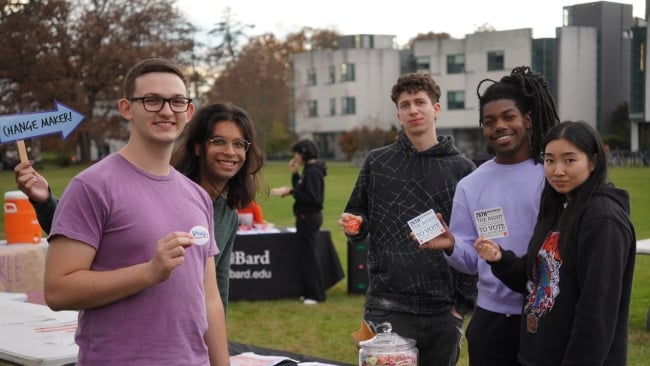 A group of Bard students stand holding voting buttons and cards about the 26th Amendment.