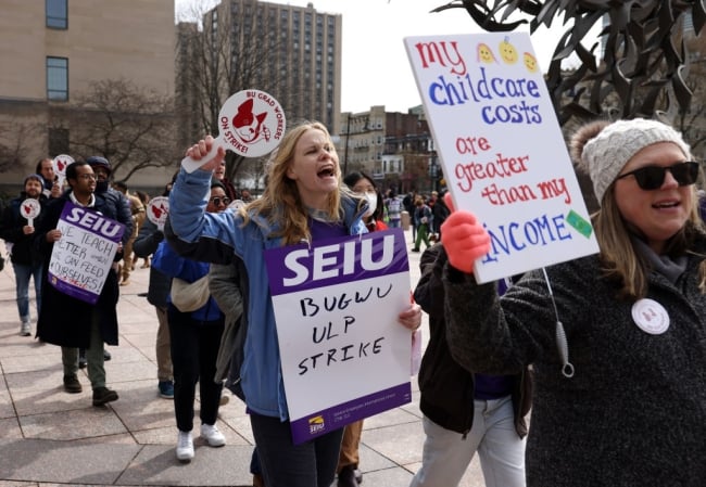 Marching graduate students holding up signs