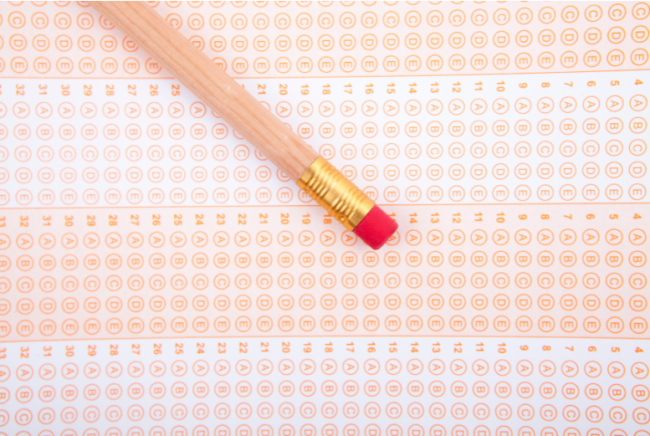 A number 2 pencil lies on a blank standardized test answer sheet filled with multiple choice bubbles.