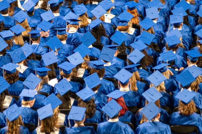 Student audience wearing gown and mortarboards during a graduation ceremony.