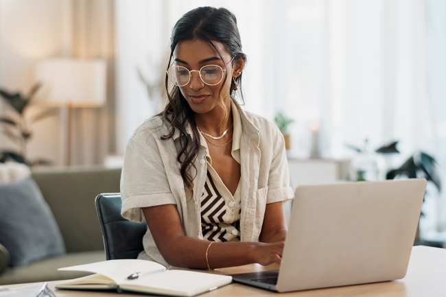 Woman, working from home with a notebook and laptop for online research.