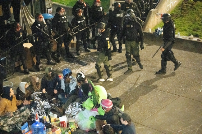 A photo showing many police officers standing in a line near a circle of protesters.