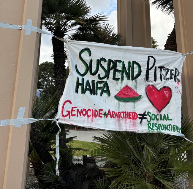 A sign reads “Suspend Pitzer Haifa” in capital letters with a picture of a watermelon and a heart.