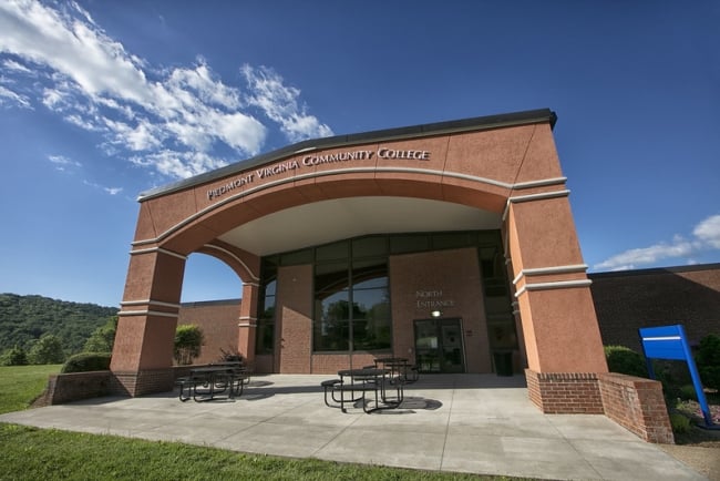 An academic building reads Piedmont Virginia Community College against a blue sky.