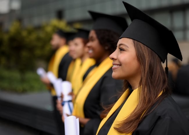 Happy group of graduating students in a row holding their diplomas