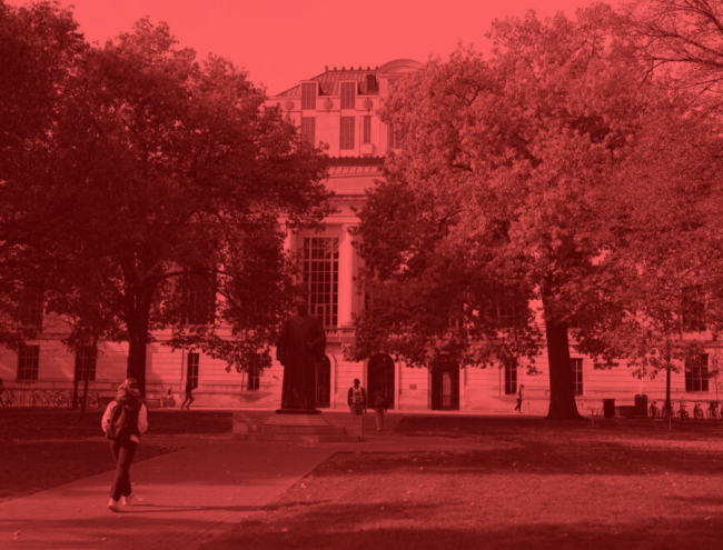 A student walks on a college campus, but the image is entirely red and black