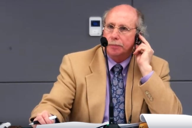 Andy Everman, the chair of Mott Community College, sits in front of a microphone. 