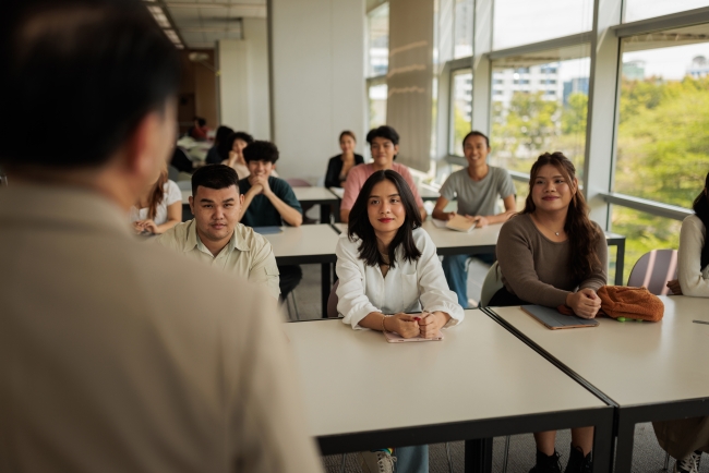 View of the back of the head of an instructor lecturing a diverse classroom