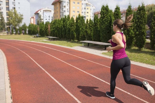 A woman runs on a track in front of residential buildings