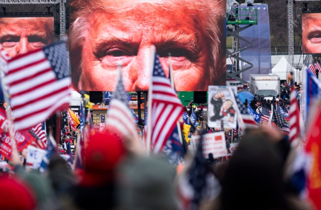 Large images of former president Trump's face on video screens loomed over a crowd of his supporters, many bearing American flags, as they gathered at the White House on Jan. 6, 2021.
