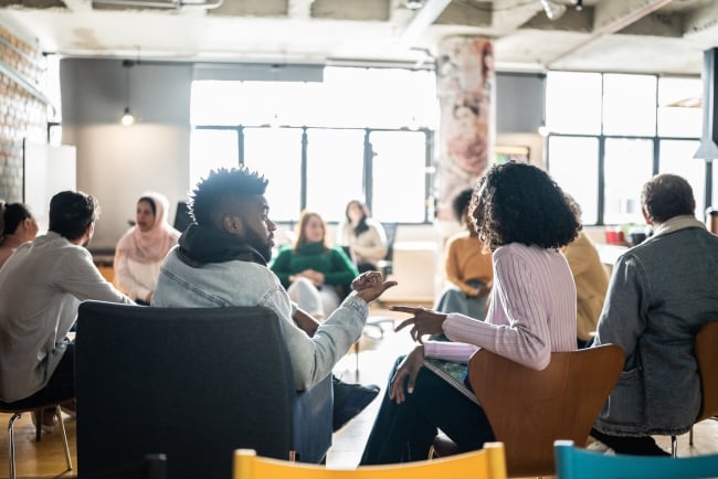 Two students talk to one another in a larger group setting