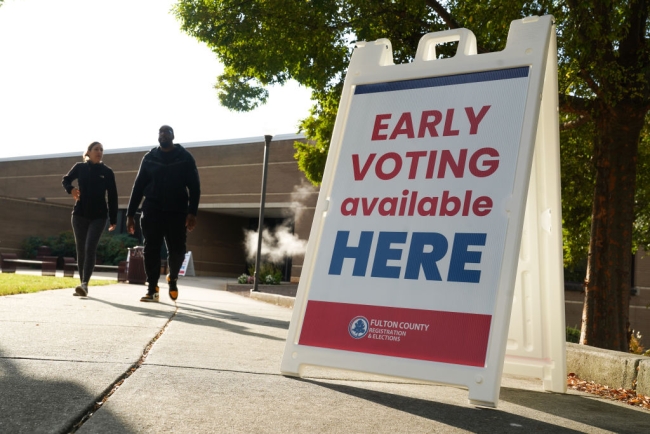 A sign that says Early voting available here stands on a sidewalk