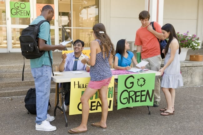 A group of students discusses climate change and sustainability on a college campus.