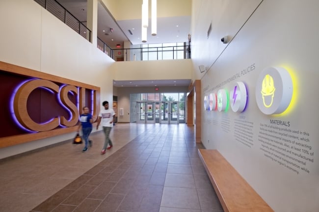 Two students walk down a hallway that reads "CSU" in large letters.