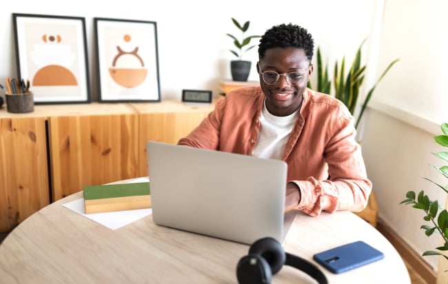 Black male university student studying at home using laptop