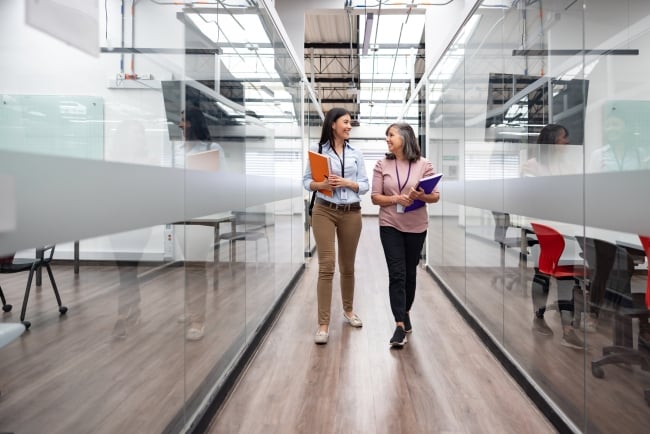 A young woman and older woman walk down a hall in a university