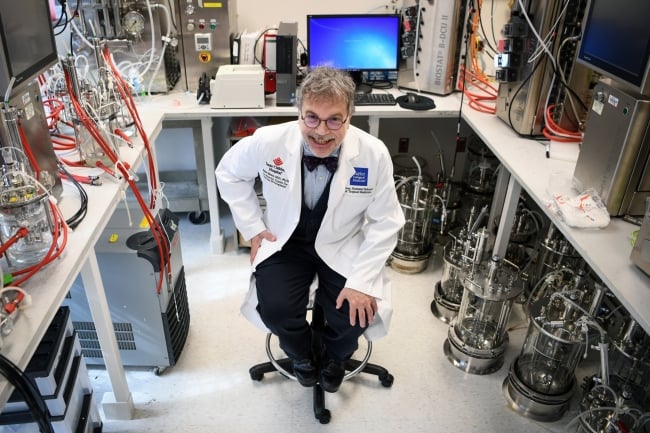 A photograph of Dr. Peter Hotez in a white lab coat, surrounded by technology.