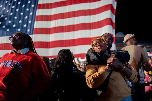 People hug each other at Howard, an American flag is behind them