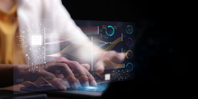 A programmer works on a laptop looking at charts and code
