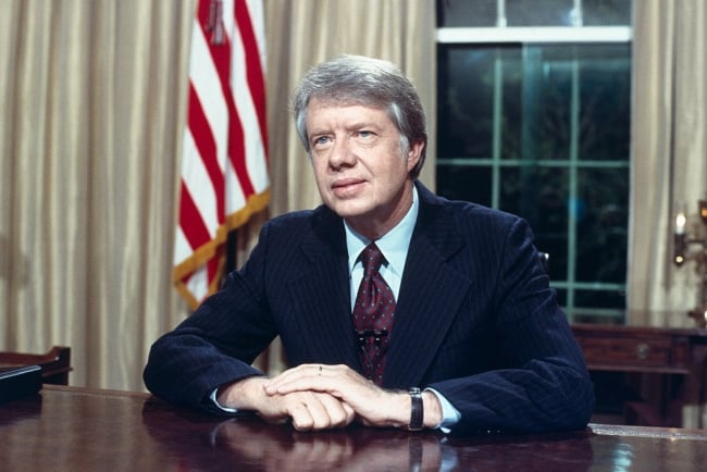Former president Jimmy Carter, who died Dec. 29, is seated at his desk in the Oval Office on April 18, 1977. 