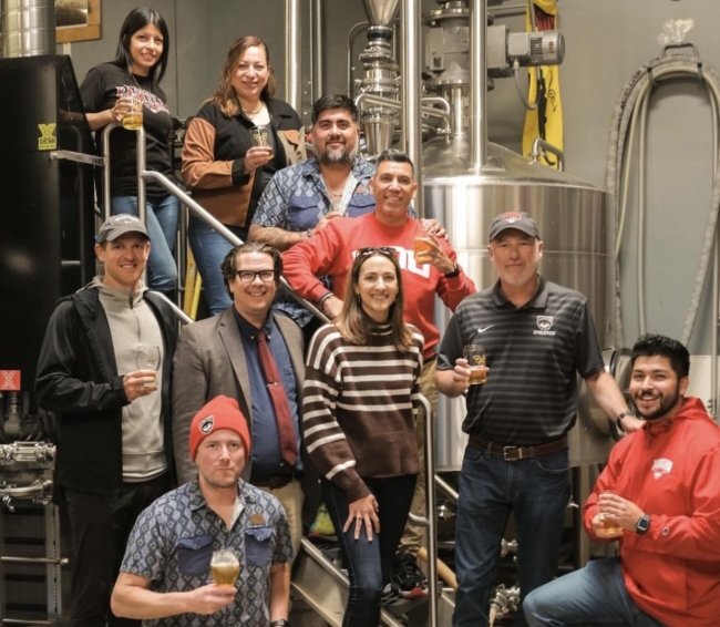 Staff from Western Oregon University and Xicha Brewing pose for a photo holding draft beers