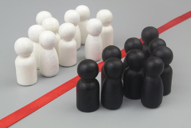 Groups of white and black people-like figurines are divided from one another by color, with a red line separating the two groups.
