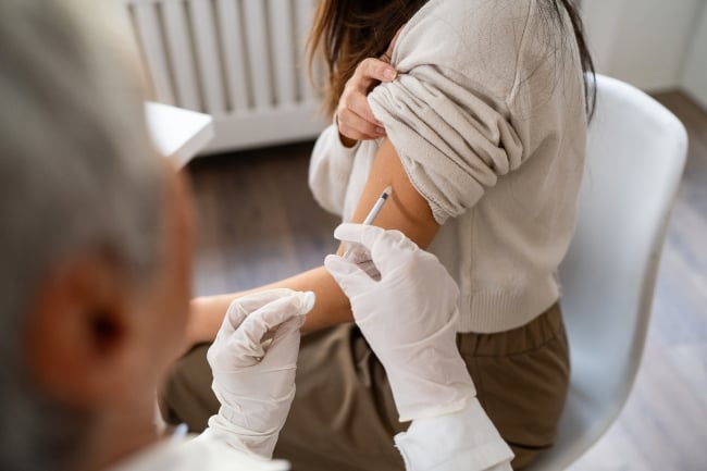 Senior Caucasian female doctor, giving a flu vaccine to a female patient Japanese ethnicity, during an annual medical check-up