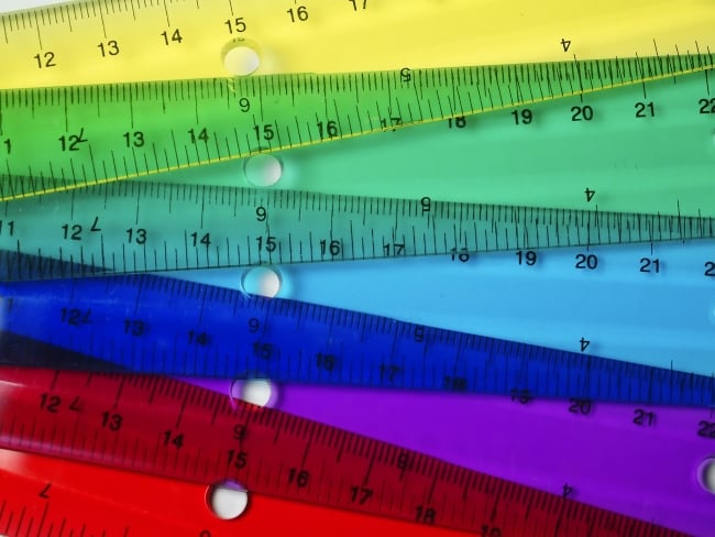 Rulers of different colors overlap with one another, creating a rainbow-like effect.