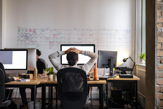 Young professional sits stressed working at a desk.