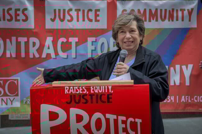 AFT president Randi Weingarten speaks in May 2024 in front of a sign that says Raises Justice Community