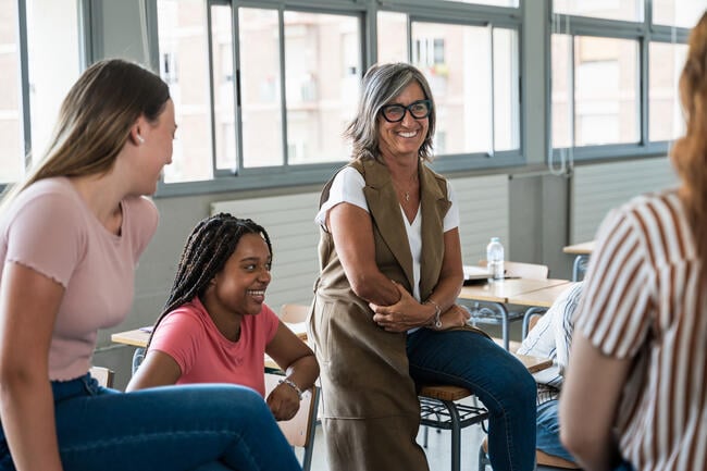 A photo of two women students laughing along with a female professor.