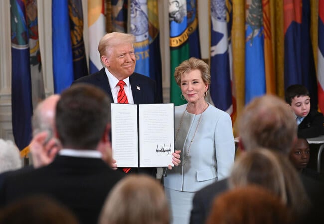 A photo of President Trump and Secretary of Education Linda McMahon: Trump holds up his signed executive order directing the dismantlement of the Department of Education. Both are smiling.