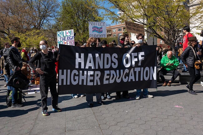 Protesters hold a bold sign that reads "hands off higher education."