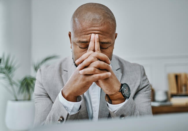 A man leans his head against his hands in an office.