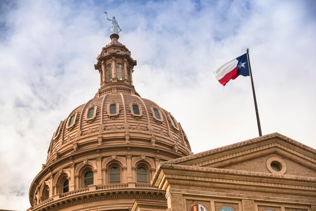 The dome of the Texas capitol, with the Texas state flag flying in front.