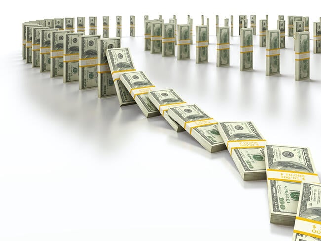 Stacks of $100 bills are lined up to mimic dominoes falling.