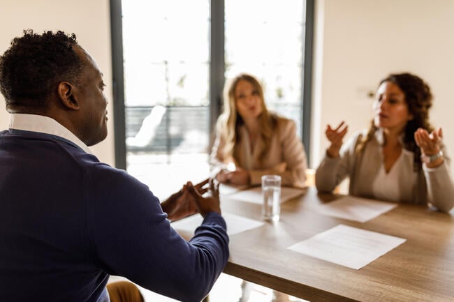 A photo of a job candidate meeting with two interviewers; they are engaged in an animated discussion.