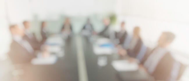 A blurry, out-of-focus picture of a group of trustees around a board table.