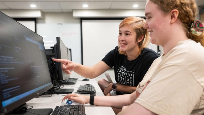 Two students work together at Champlain College at a computer lab