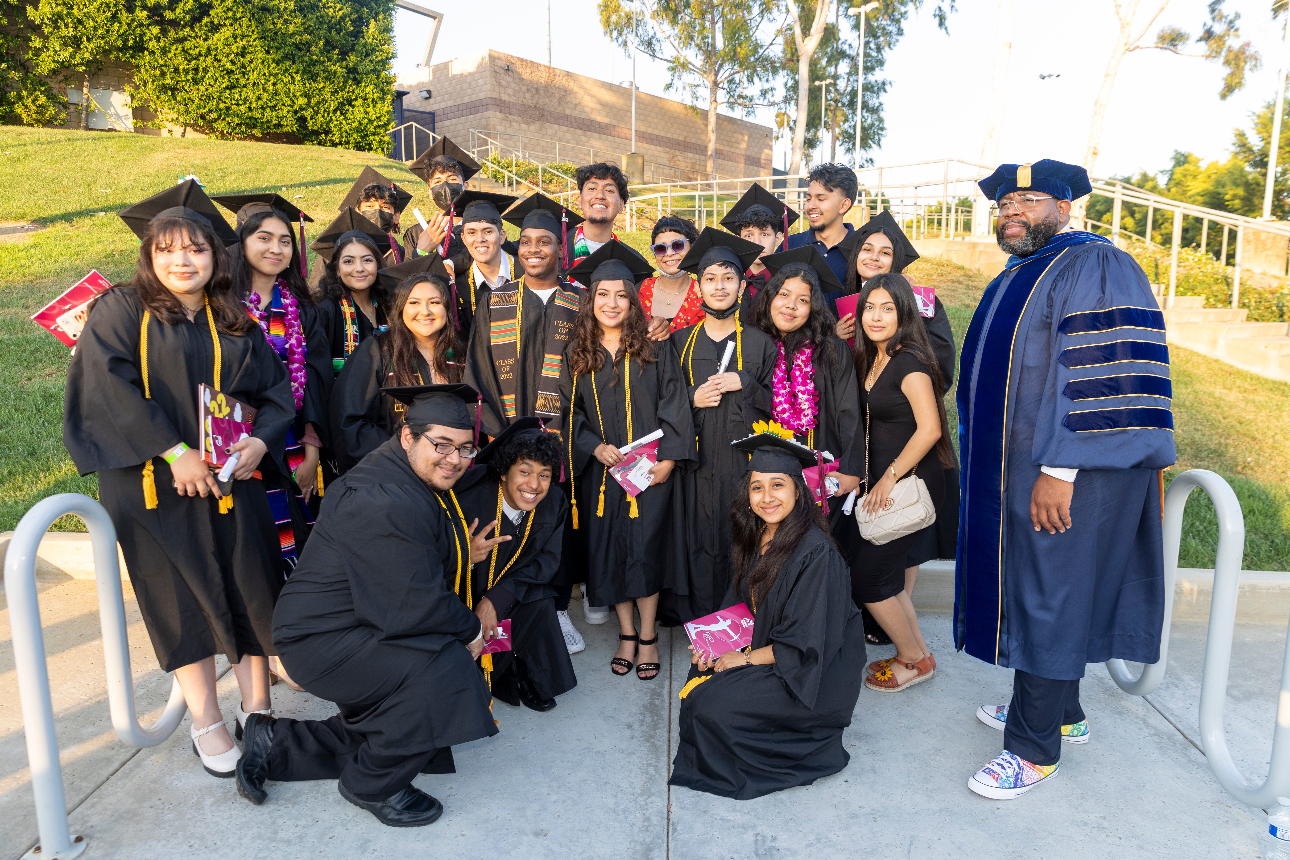 Keith Curry, at right, wearing his cap and gown and Chuck Taylor sneakers, with a group of graduating students during Compton College's 2022 commencement ceremony.