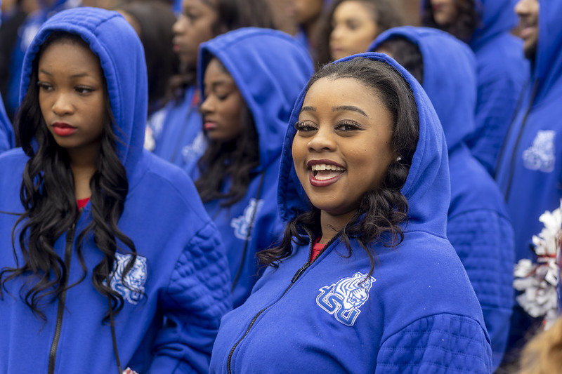 Two young Black women in blue hooded sweatshirts, both wearing bright lipstick.