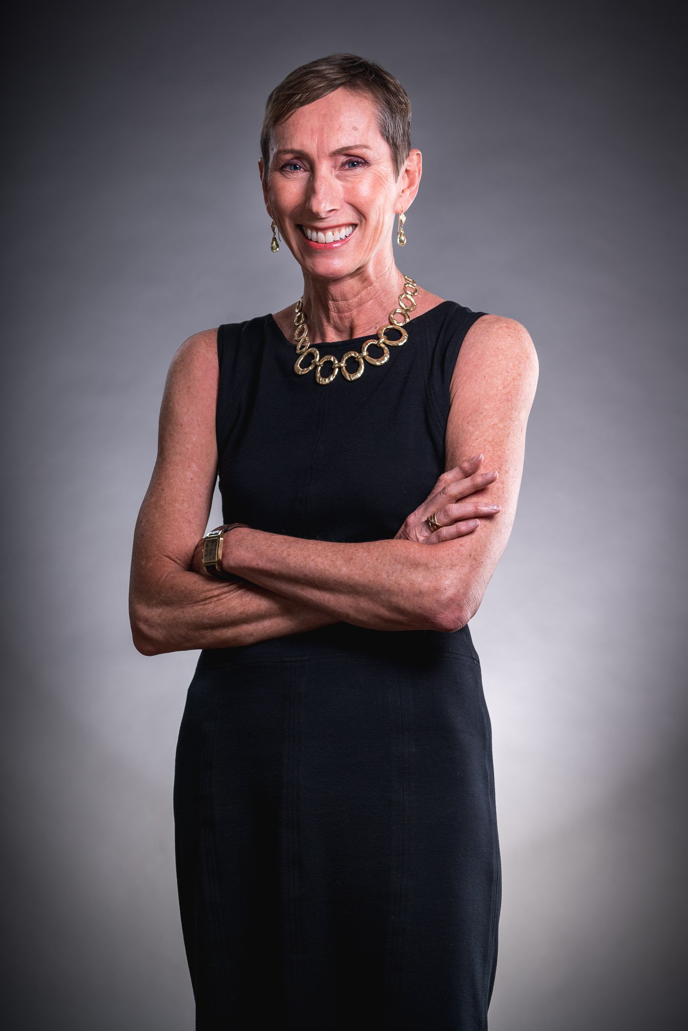 Betty Vandenbosch, a white woman with short dark hair wearing a black dress and a statement necklace.