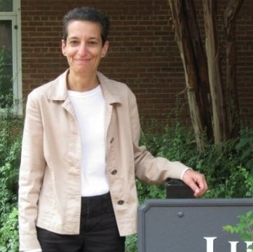 Celia Rabinowitz, a white woman with short dark hair wearing a khaki jacket over a white shirt and black pants.