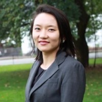 Charlotte Wang, a young Asian woman wearing a gray blazer.