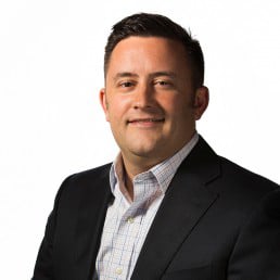 James DeVaney, a white man with dark hair wearing a collared shirt and blazer with no tie.