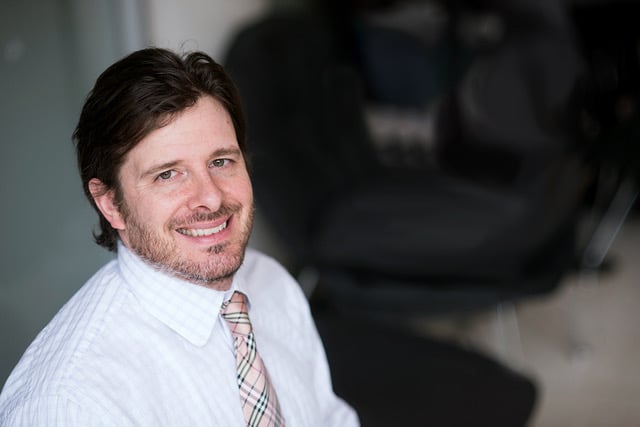 Adam Klivans, a white man with dark hair and a beard wearing a collared shirt and tie.