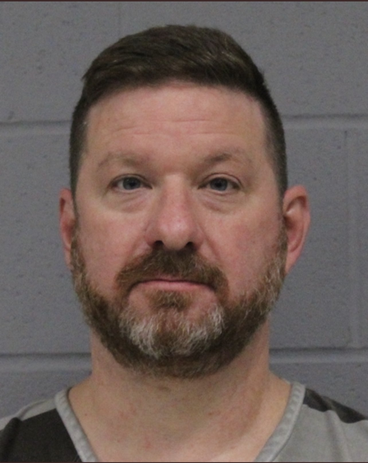 A mugshot of a bearded man