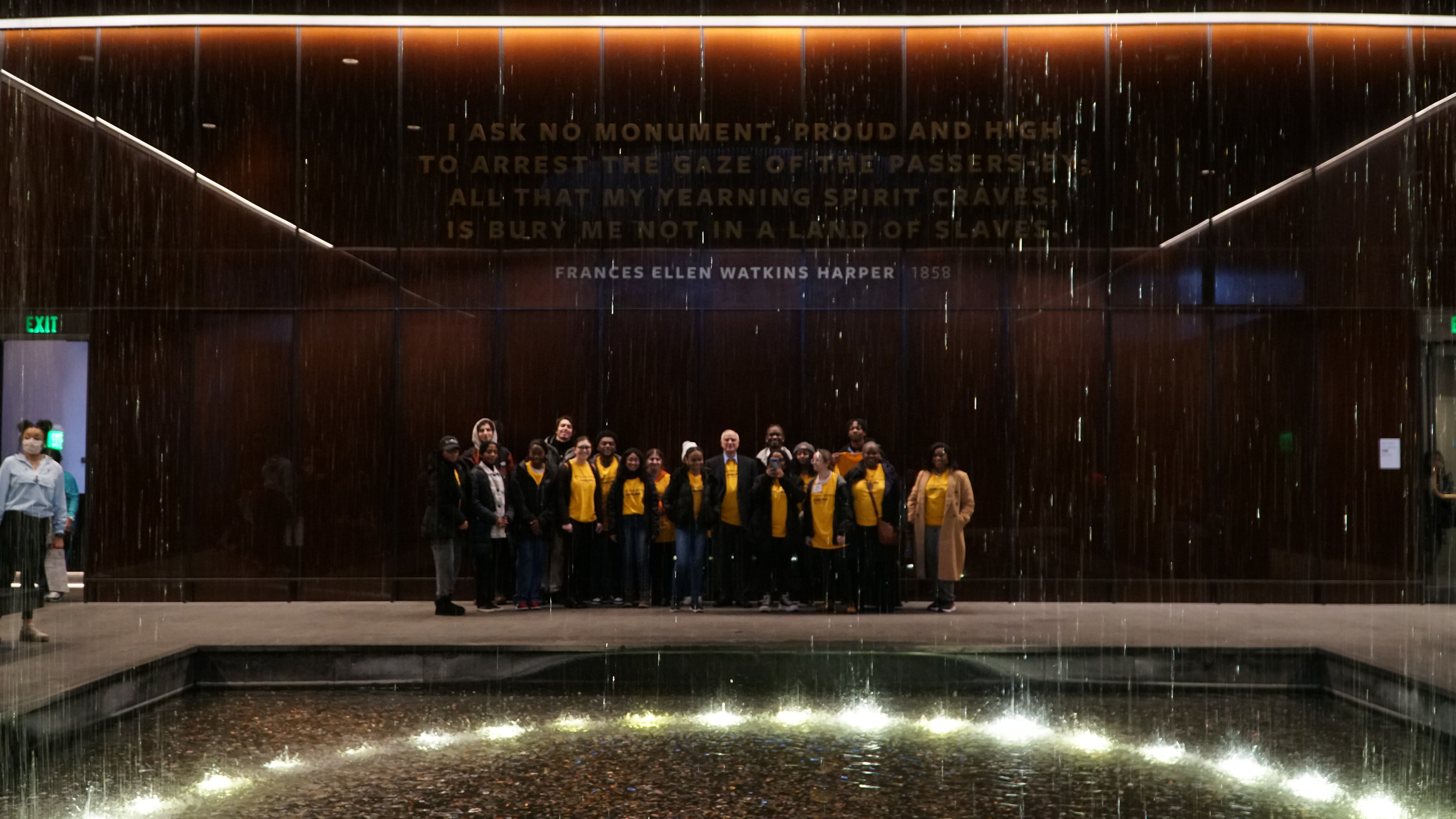 Adelphi University students stand in a group near the fountain at the National Museum of African American History and Culture. 