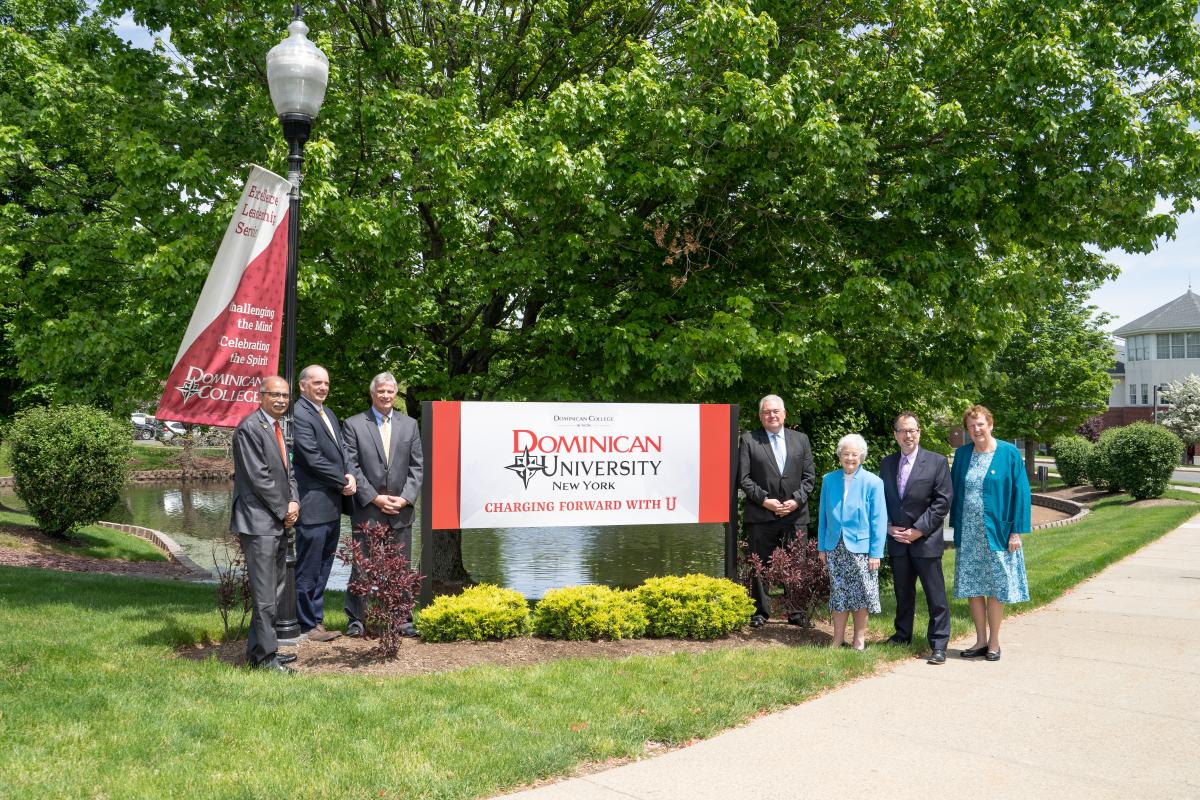 Leaders pose with the Dominican University sign.